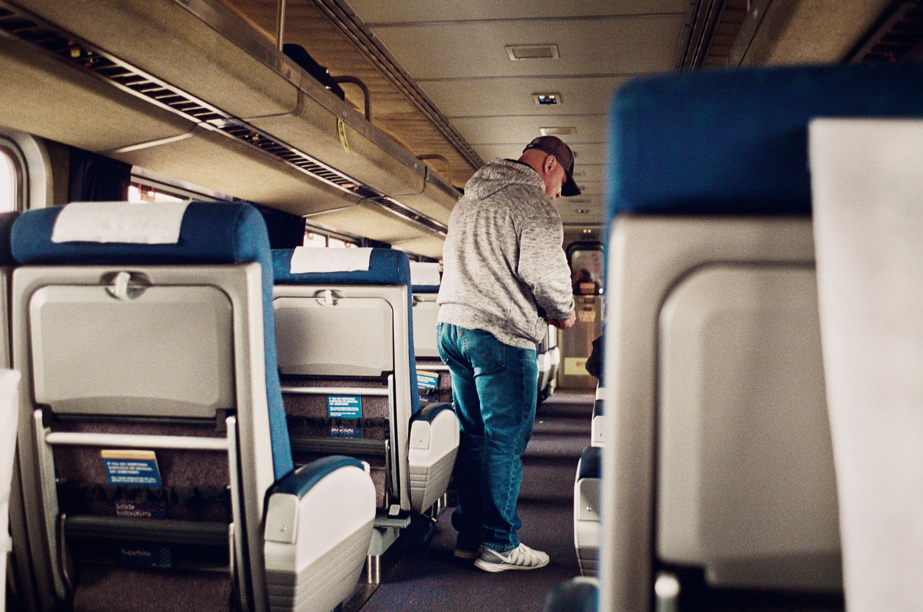 A man stands in the aisle of an empty airplane.