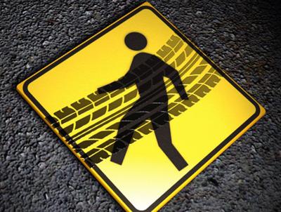 A pedestrian crossing sign lays in the road with tire tracks across it