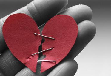 Broken paper heart stapled together.